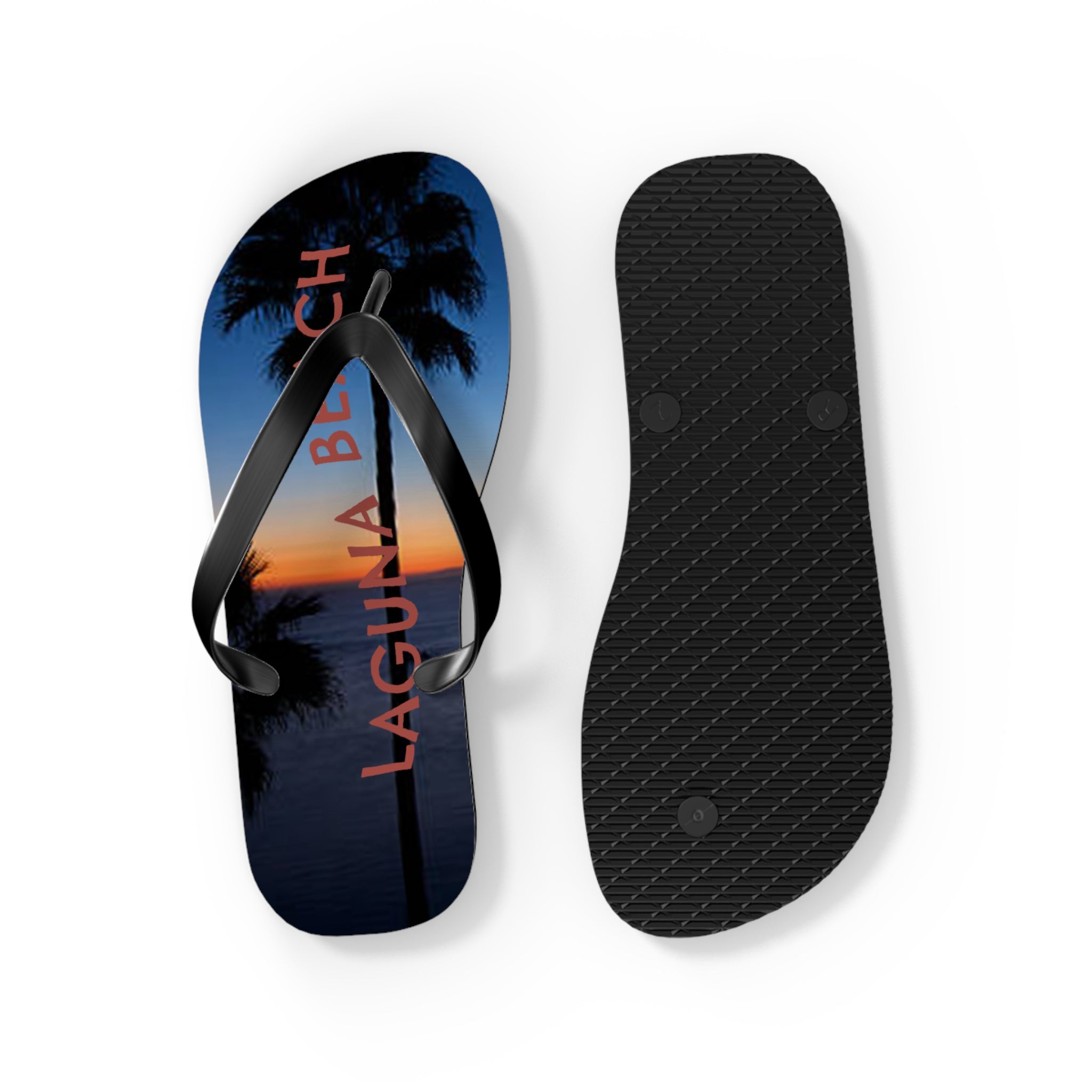 Black flip-flops with "LAGUNA BEACH" and palm tree silhouette at sunset.