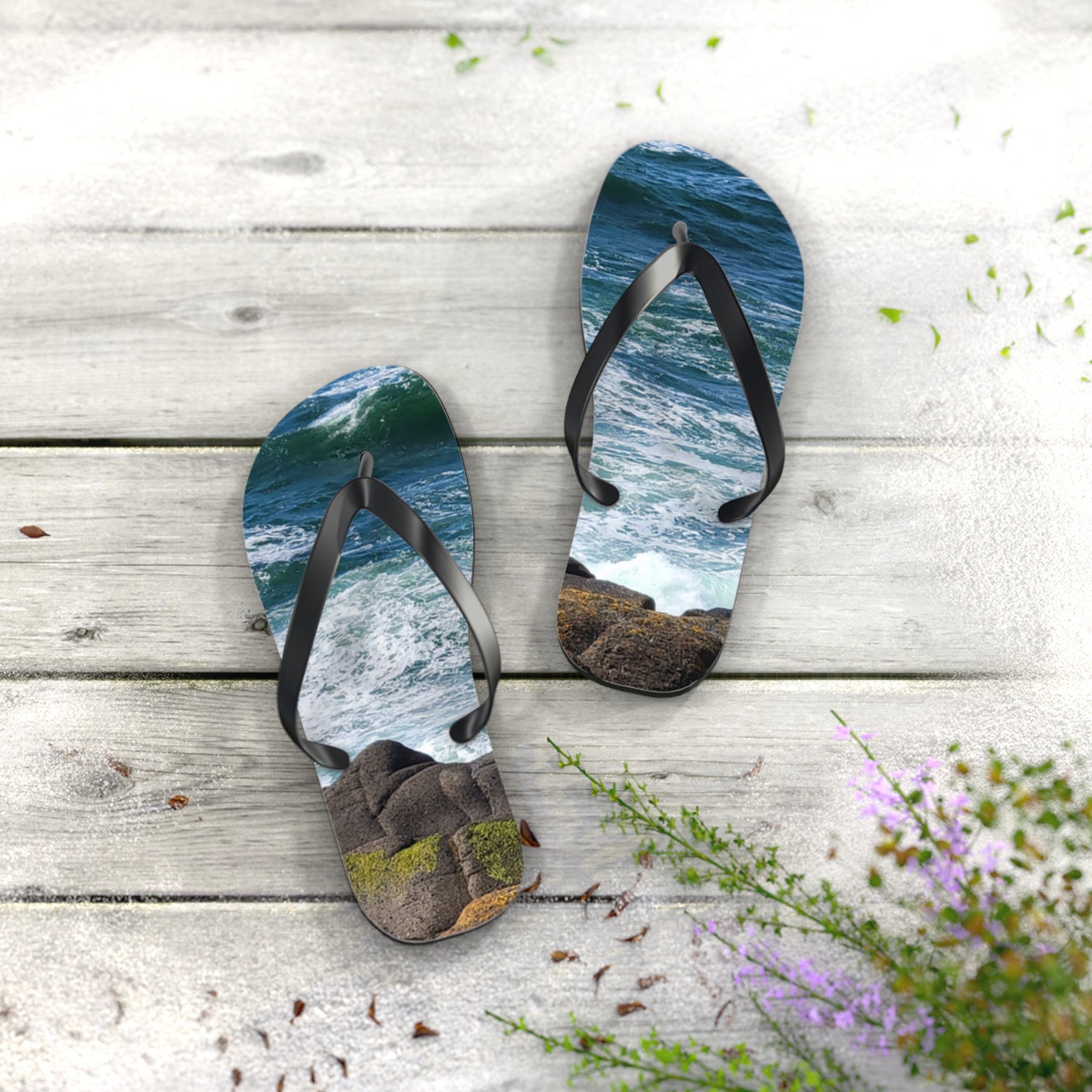 Flip-flops with ocean waves and rocks design on white wooden planks.