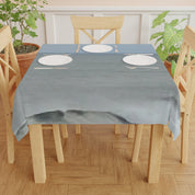Tablecloth with place settings on wooden dining table with potted plants.