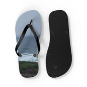 Flip flops with ocean and coastline scene on soles, white background.