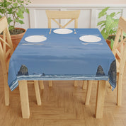 Blue tablecloth with ocean and rock formations overlay on a wooden table.