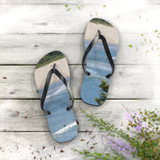 Flip-flops with ocean waves and surfer on a wooden surface.