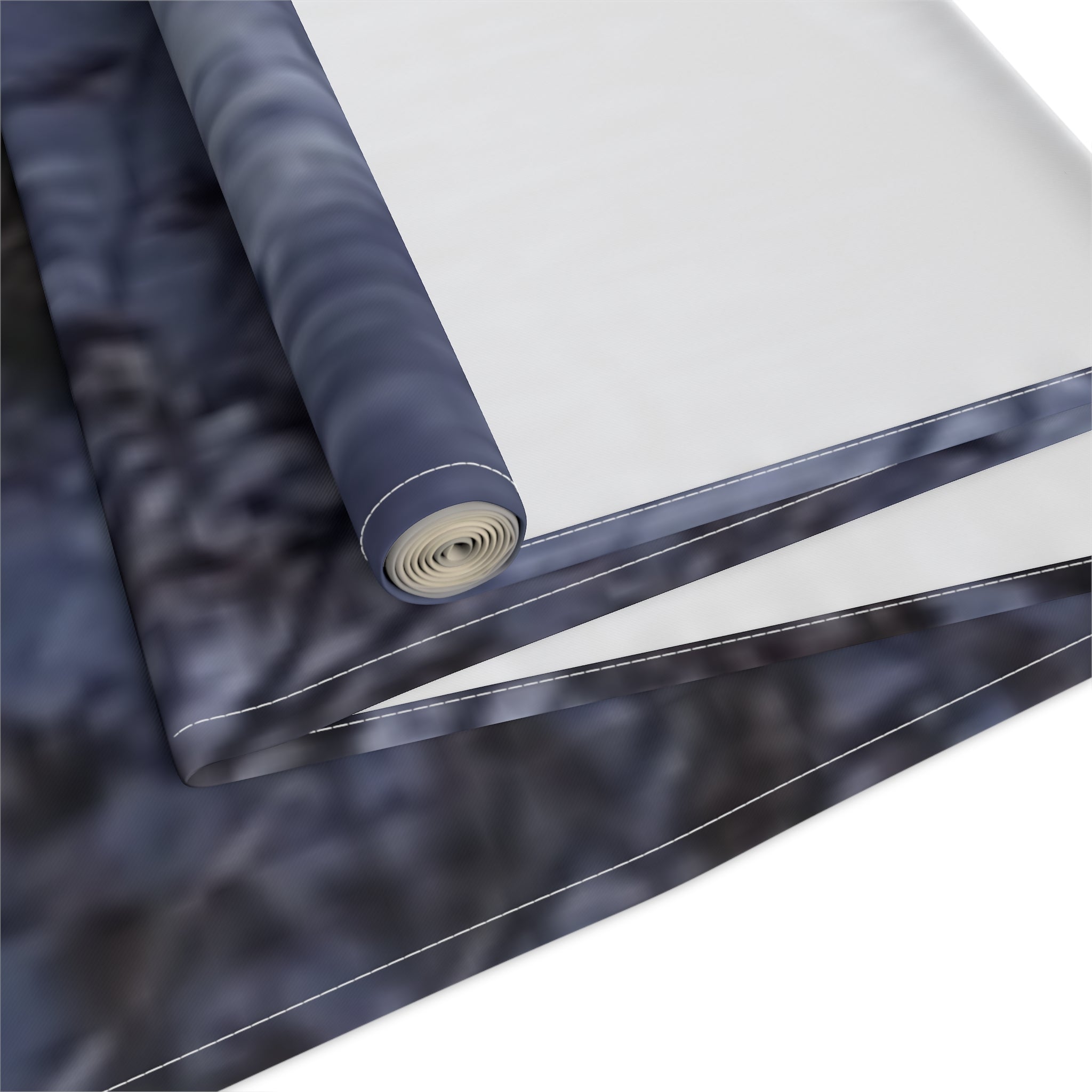 Rolled tapestry with a dark, abstract pattern on a white background.