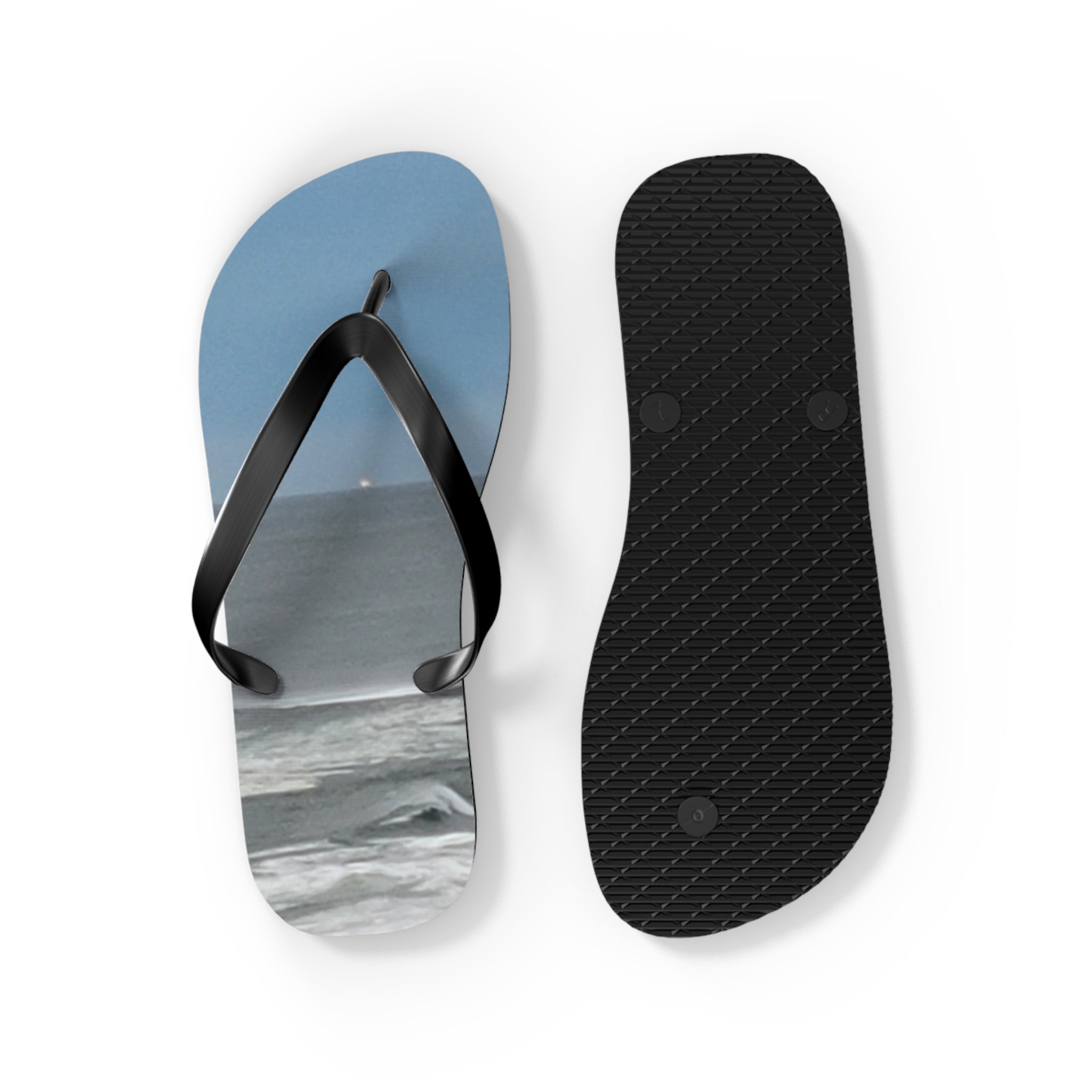 Flip-flops with a beach scene on one sole and black textured rubber on the other.