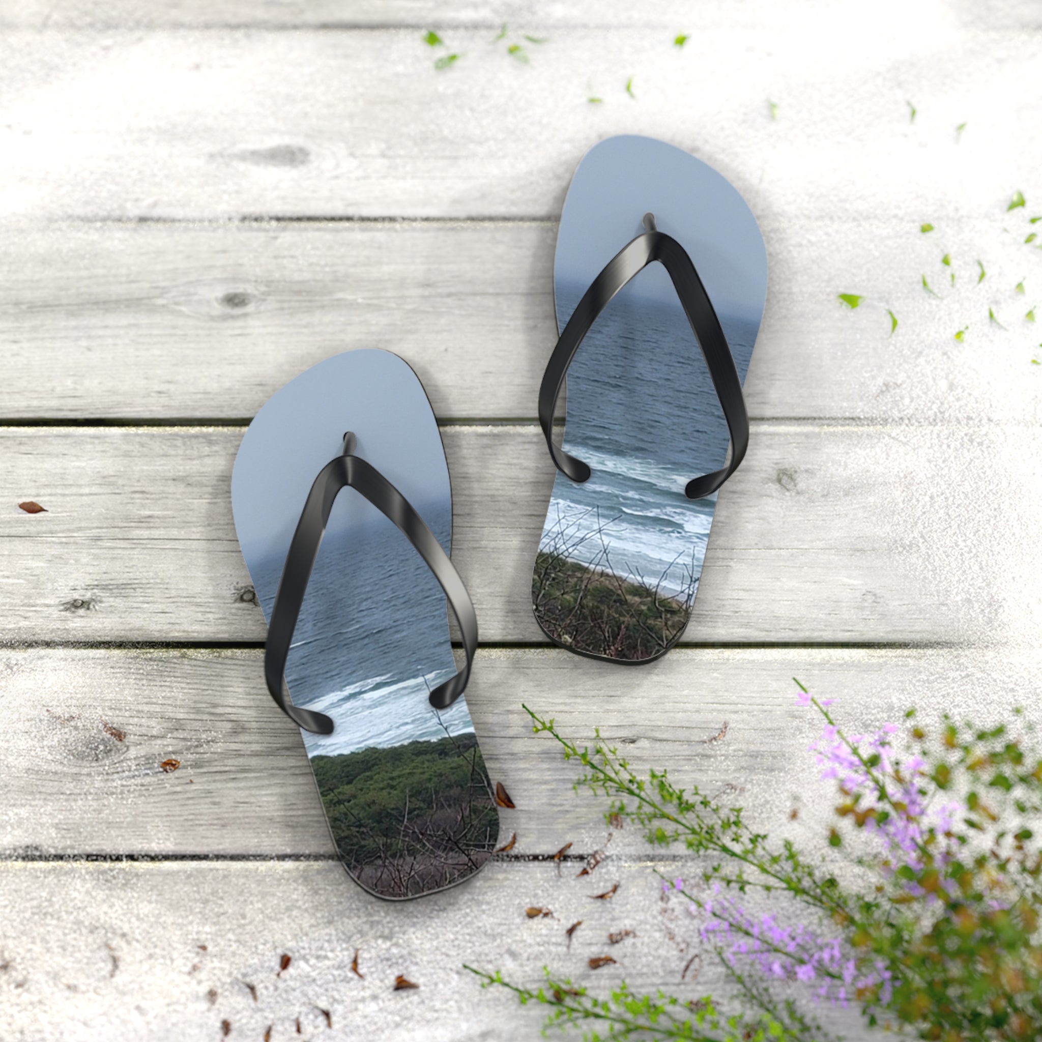 Blue flip-flops with a beach scene imprinted on the soles lie on a wooden surface.
