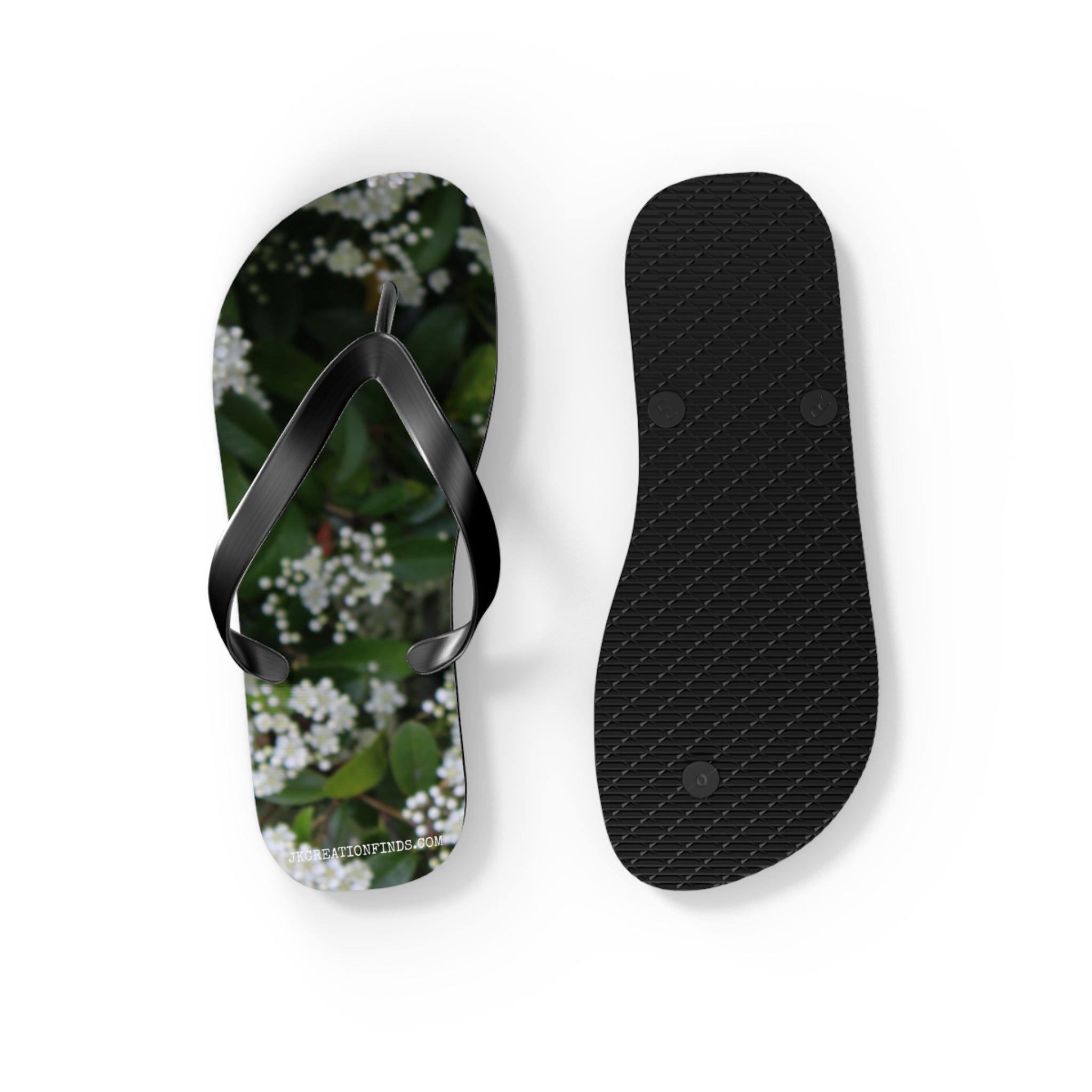 Black flip-flops with white floral pattern, one with strap, one sole-up.