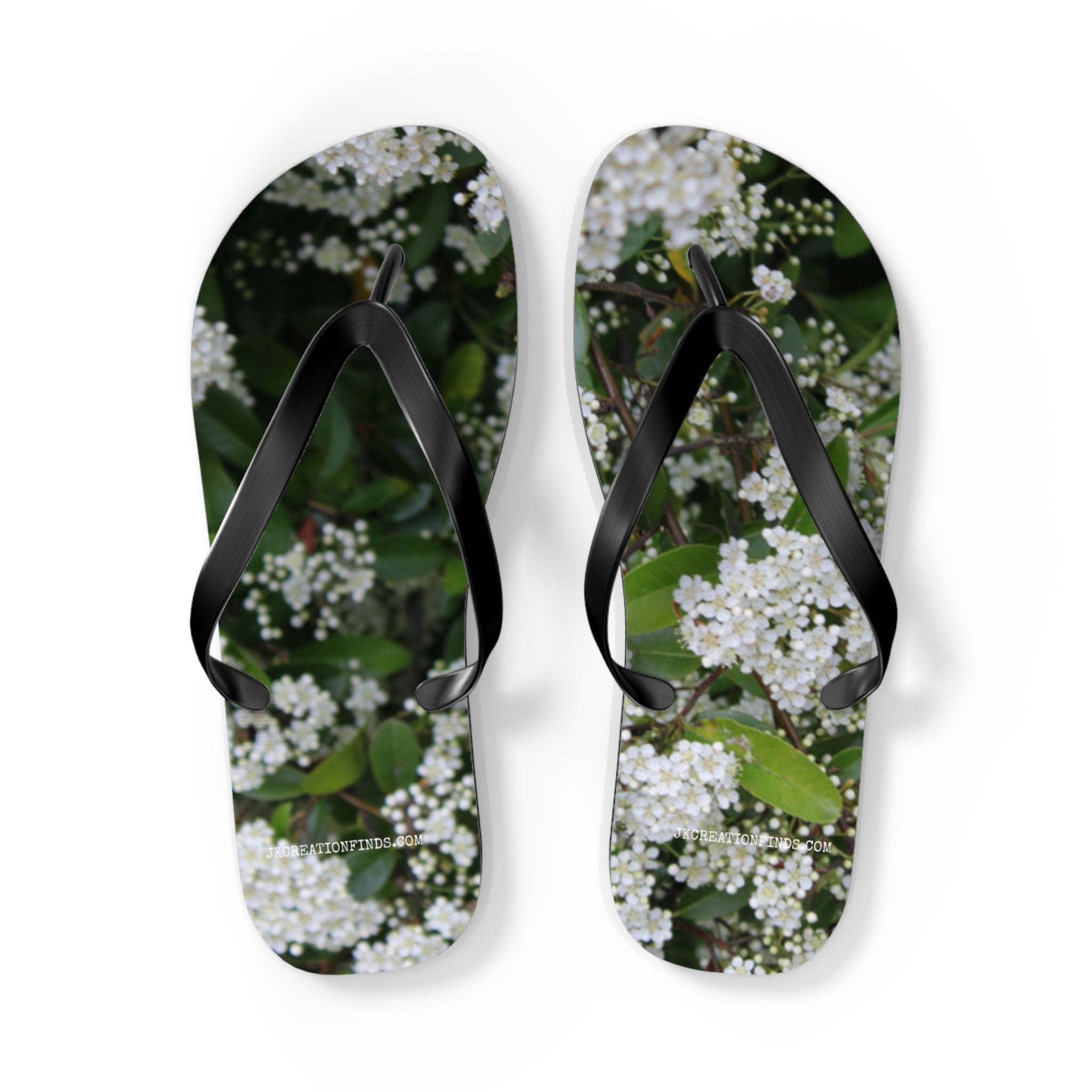 Flip-flops with white floral pattern and green leaves.