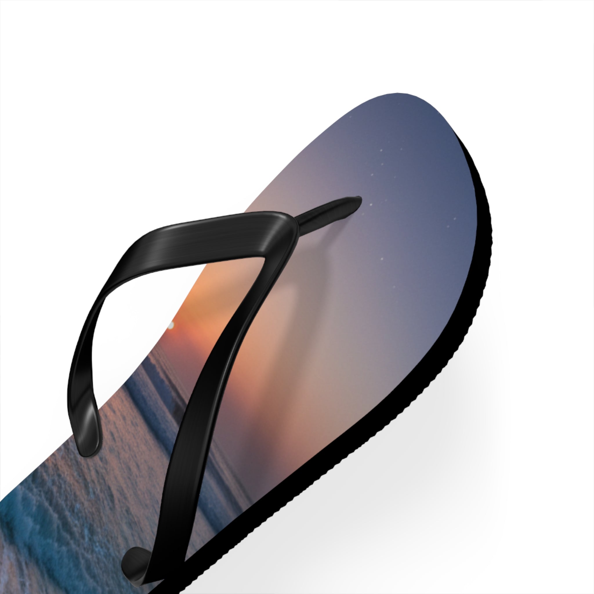 Black flip-flop with a sunset ocean wave and starry sky design.