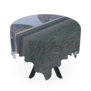 Round tablecloth with a landscape scene draped over a black table.