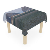 Table draped with a tablecloth featuring a distorted coastal landscape photograph.