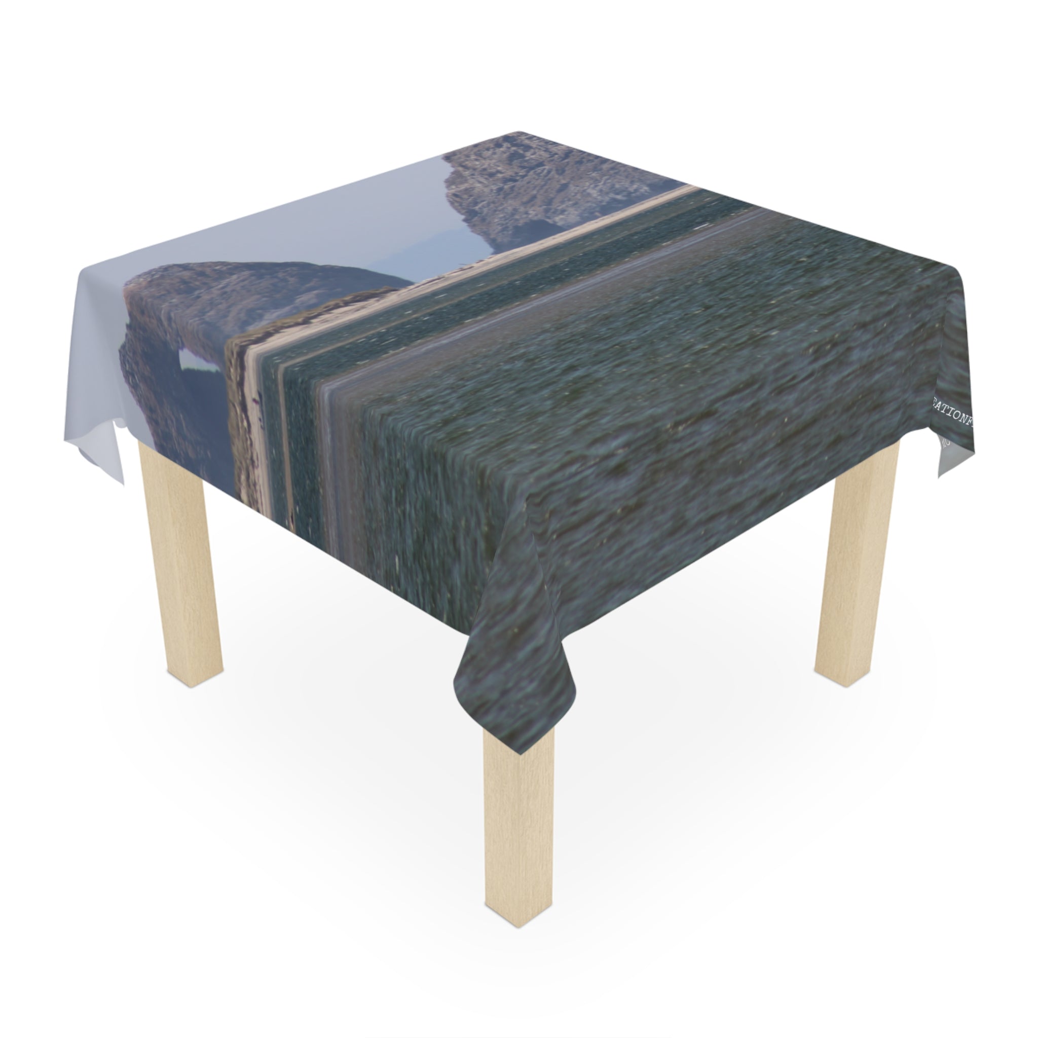 Table draped with a tablecloth featuring a distorted coastal landscape photograph.