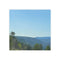 Distant blue mountains and green trees under a clear sky.