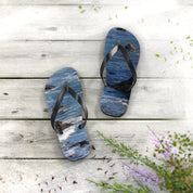 Flip-flops with a blue ocean wave pattern on a weathered wood surface.