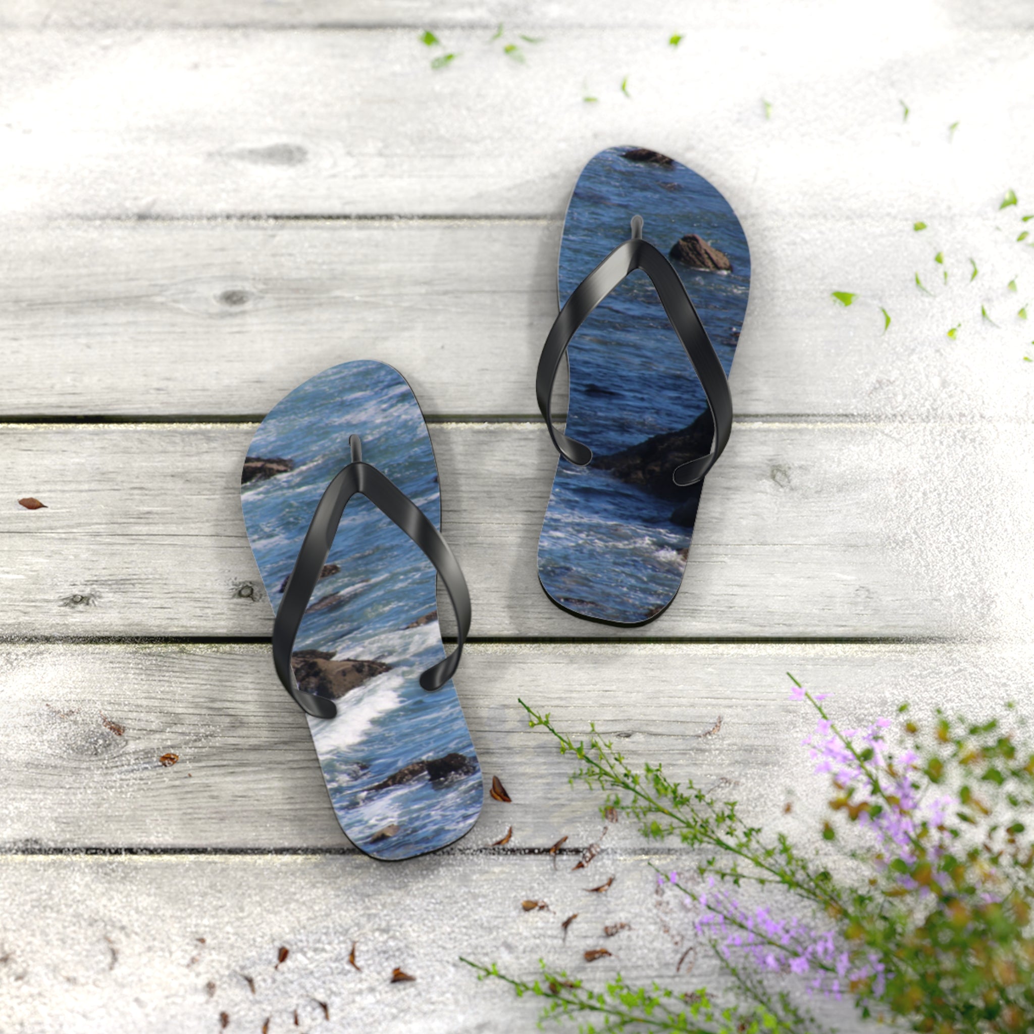 Flip-flops with a blue ocean wave pattern on a weathered wood surface.