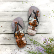 Laguna Beach flip-flops on a wooden deck with purple flowers.