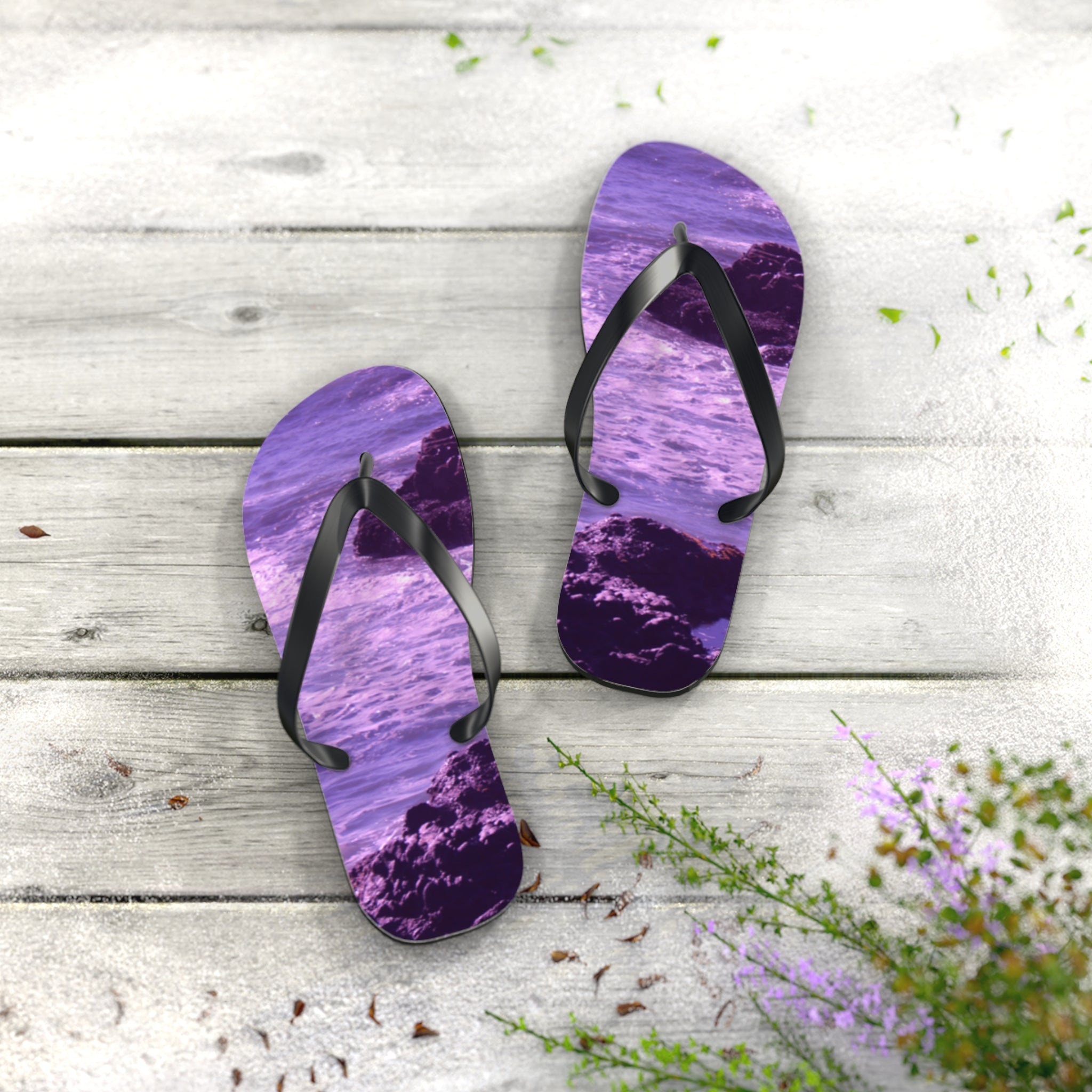 Purple flip-flops with a rocky ocean wave design on a wooden surface.