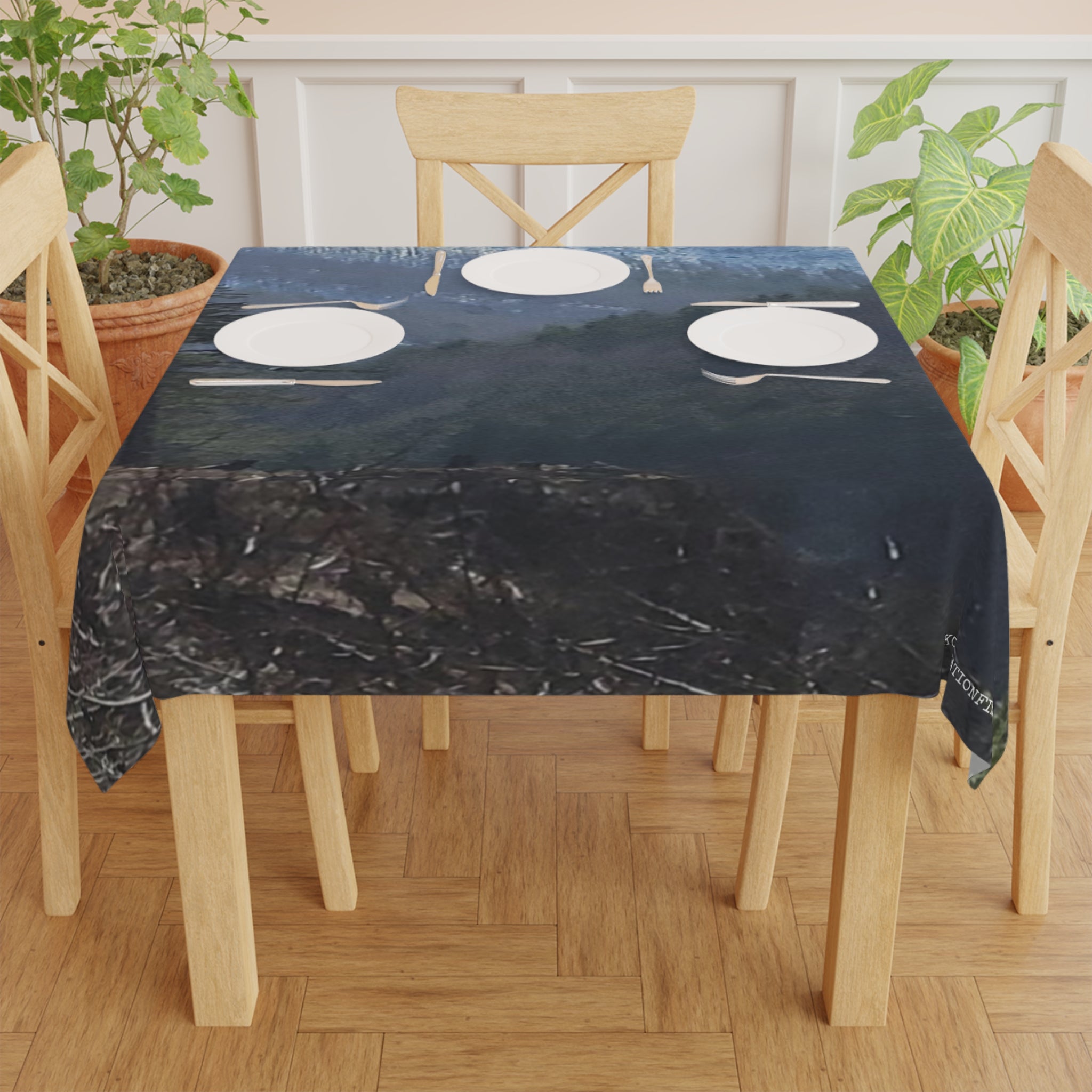 Tablecloth with a dark, textured pattern draped over a wooden table with three place settings.