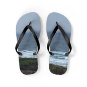 Flip-flops with a coastal ocean scene printed on the soles.