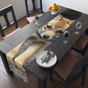 Shiba Inu puppy on a table runner draped across a dark wood dining table.