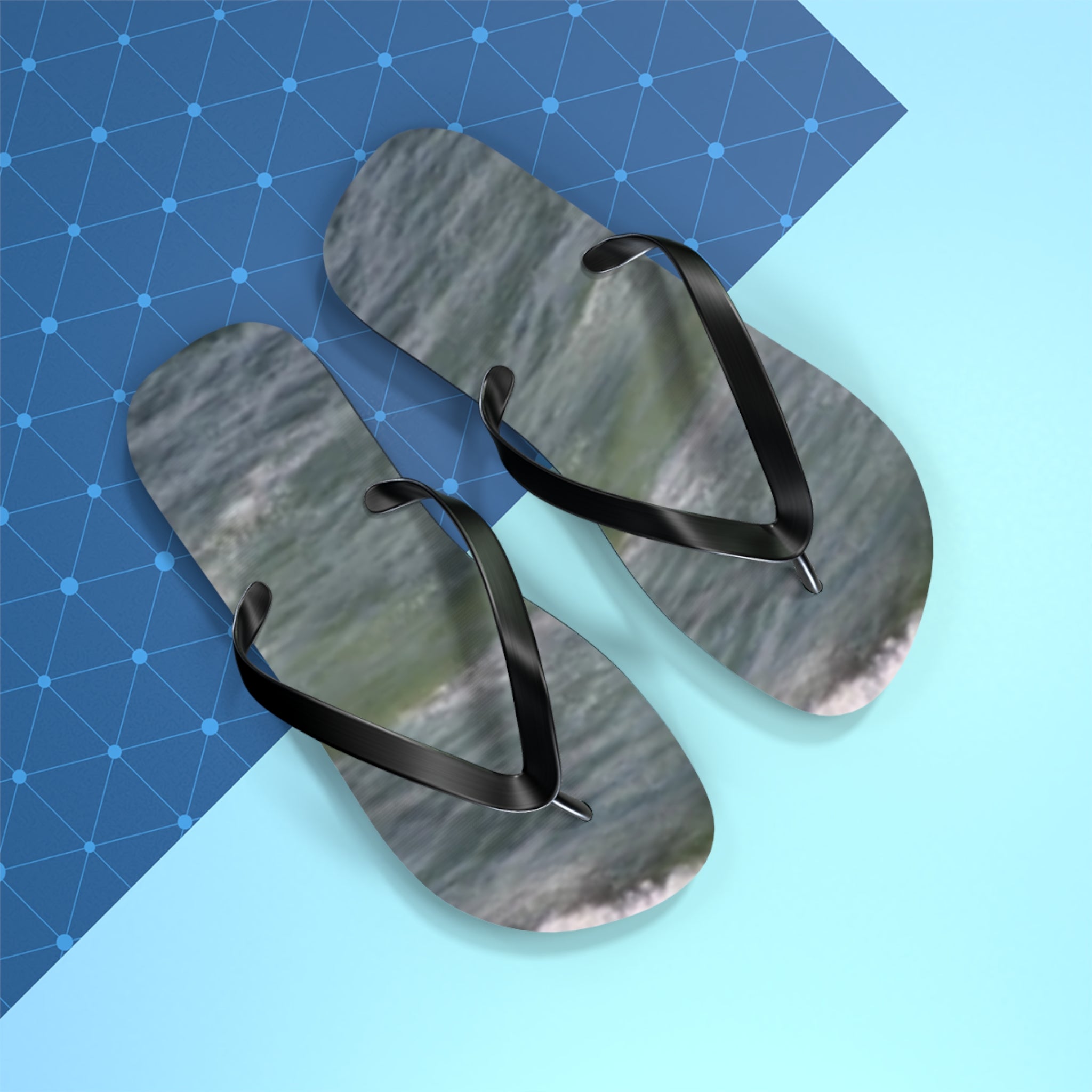 Black flip-flops with wave pattern on a blue grid and light blue background.