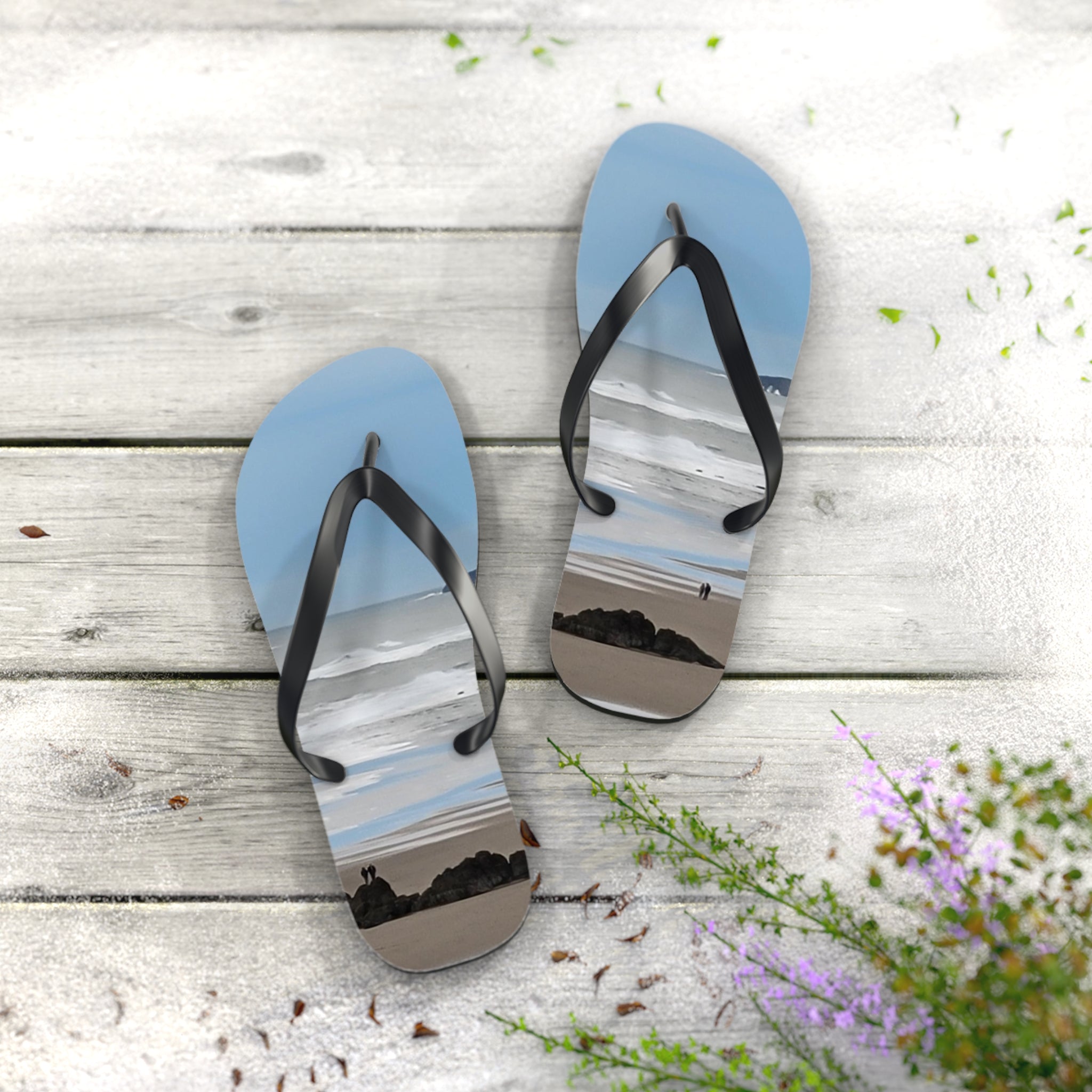 Flip-flops with a beach scene printed on the soles rest on a weathered wood surface.