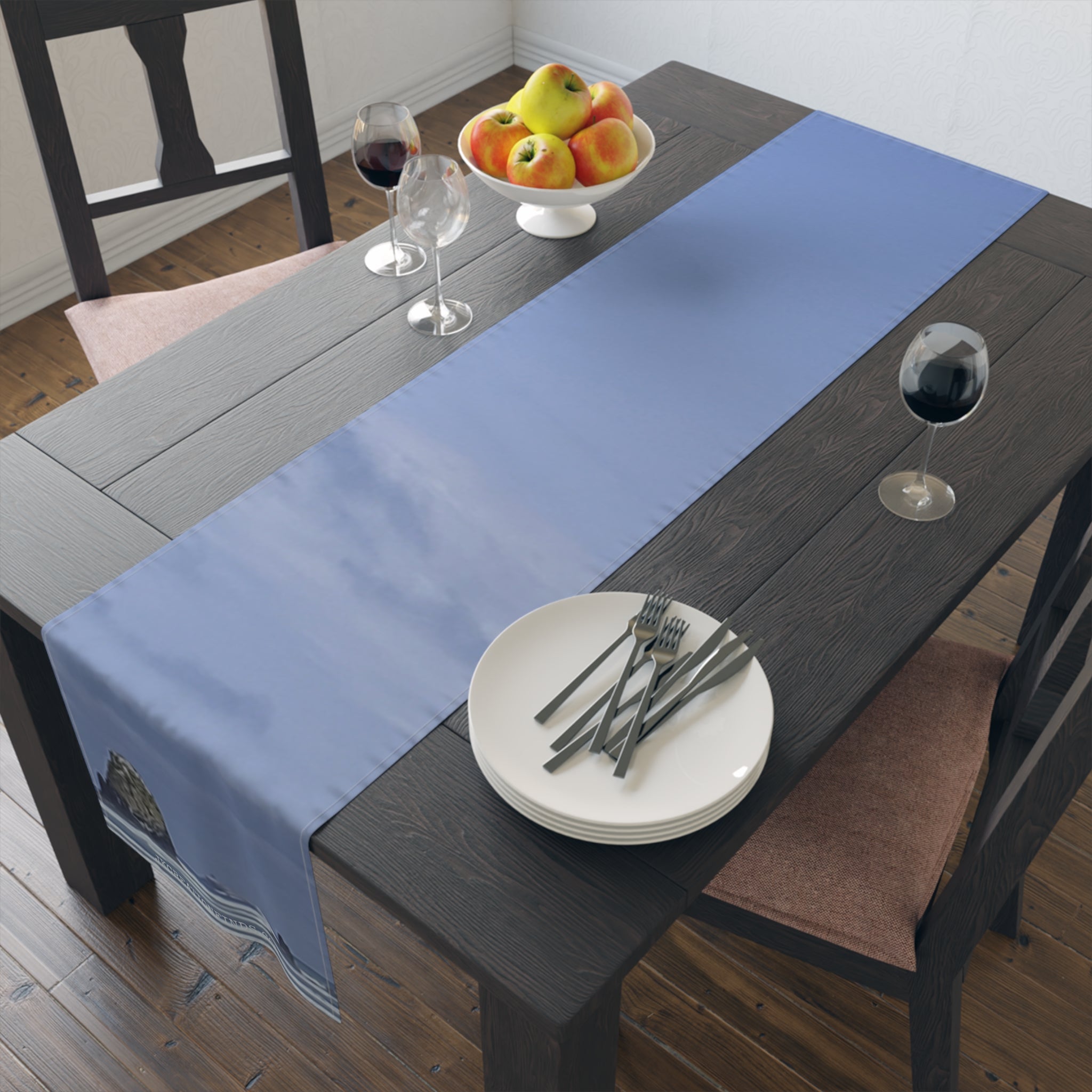 Blue table runner with a coastal landscape on a dark wood dining table.