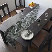Table runner with snow-covered evergreen trees and a fruit bowl on a dining table.