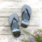 Light blue flip-flops with ocean waves printed on soles, on a wooden deck.