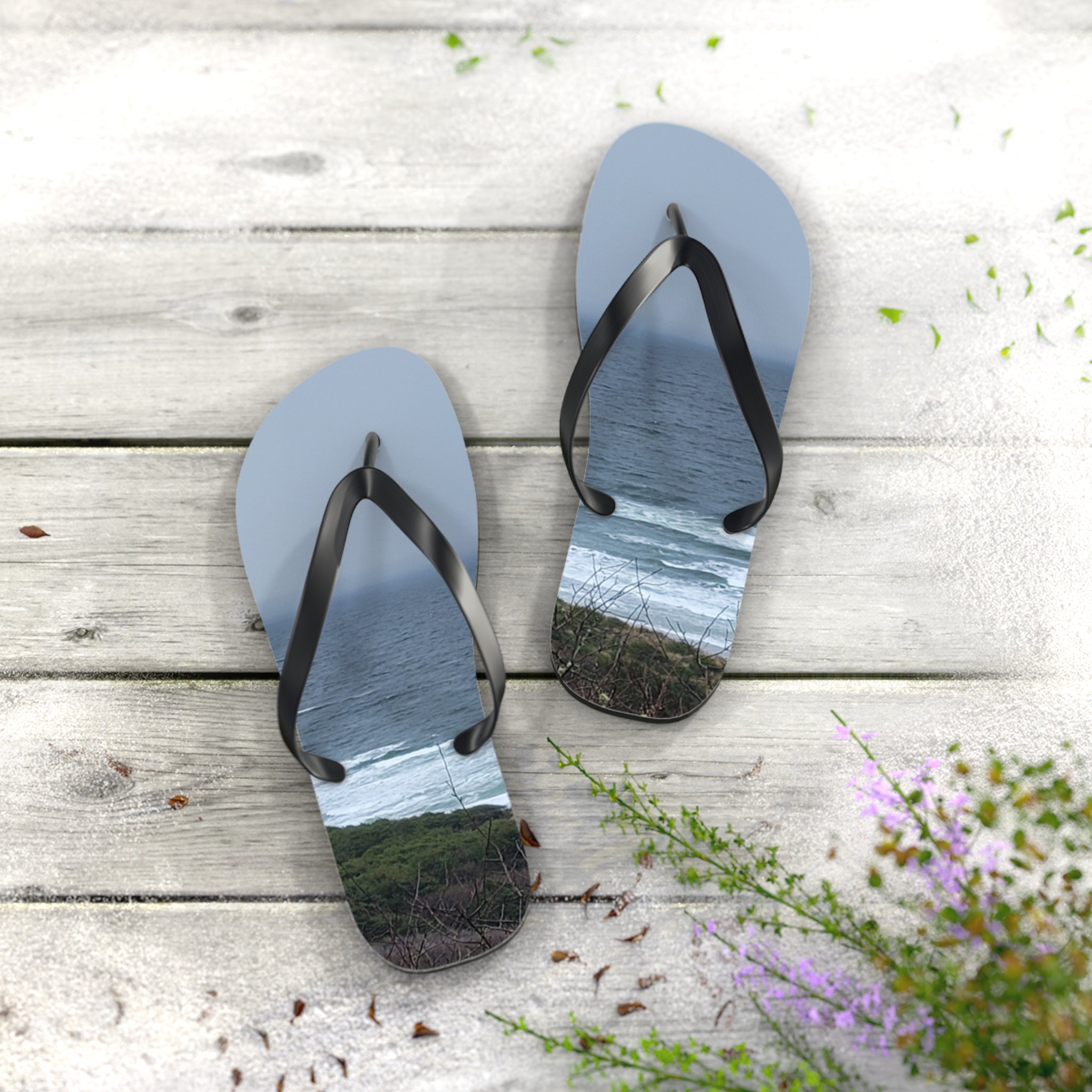 Light blue flip-flops with ocean waves printed on soles, on a wooden deck.