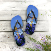 Blue flip-flops with "Laguna Beach" text and purple flowers on a wooden surface.