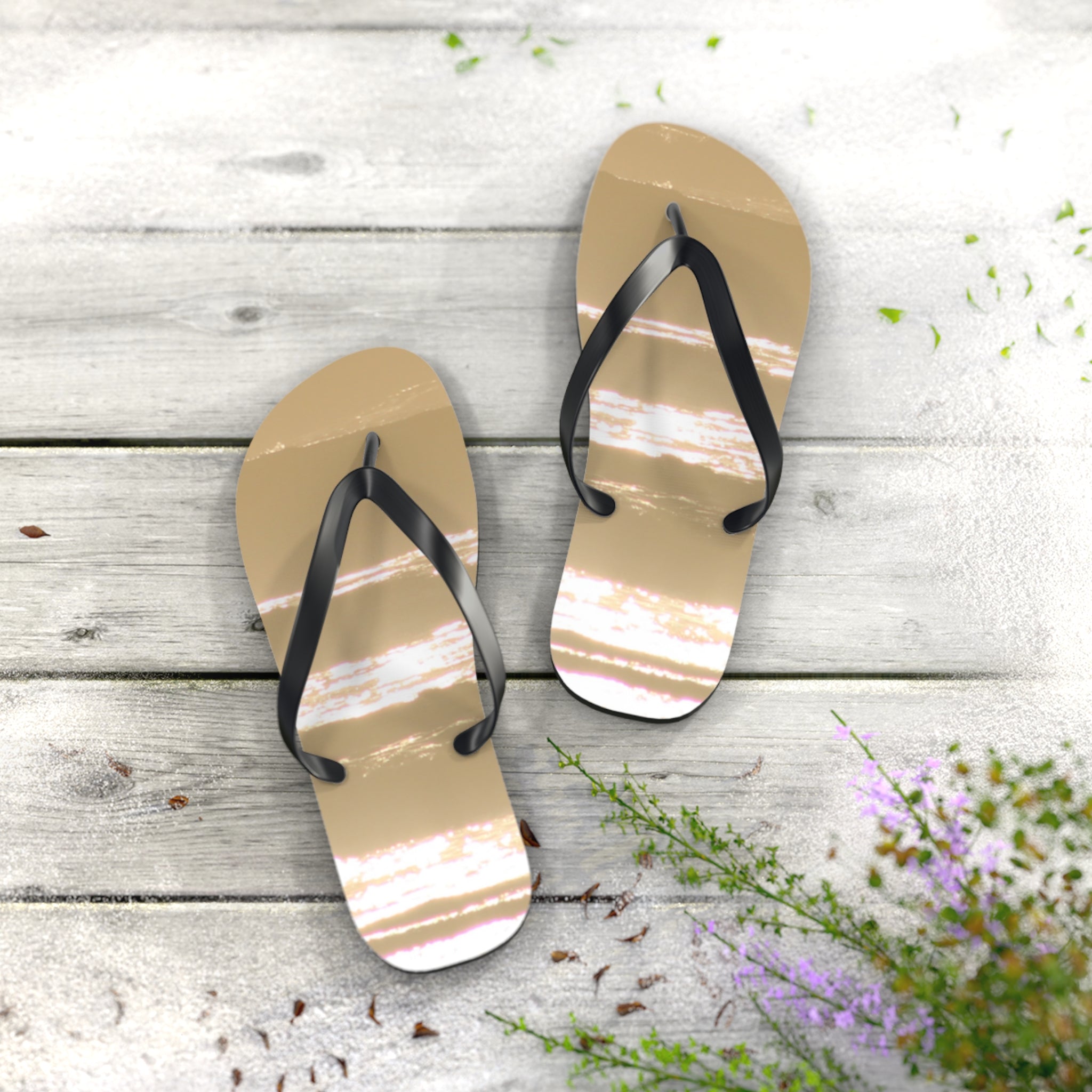 Flip flops with striped design on weathered wooden planks with scattered petals.