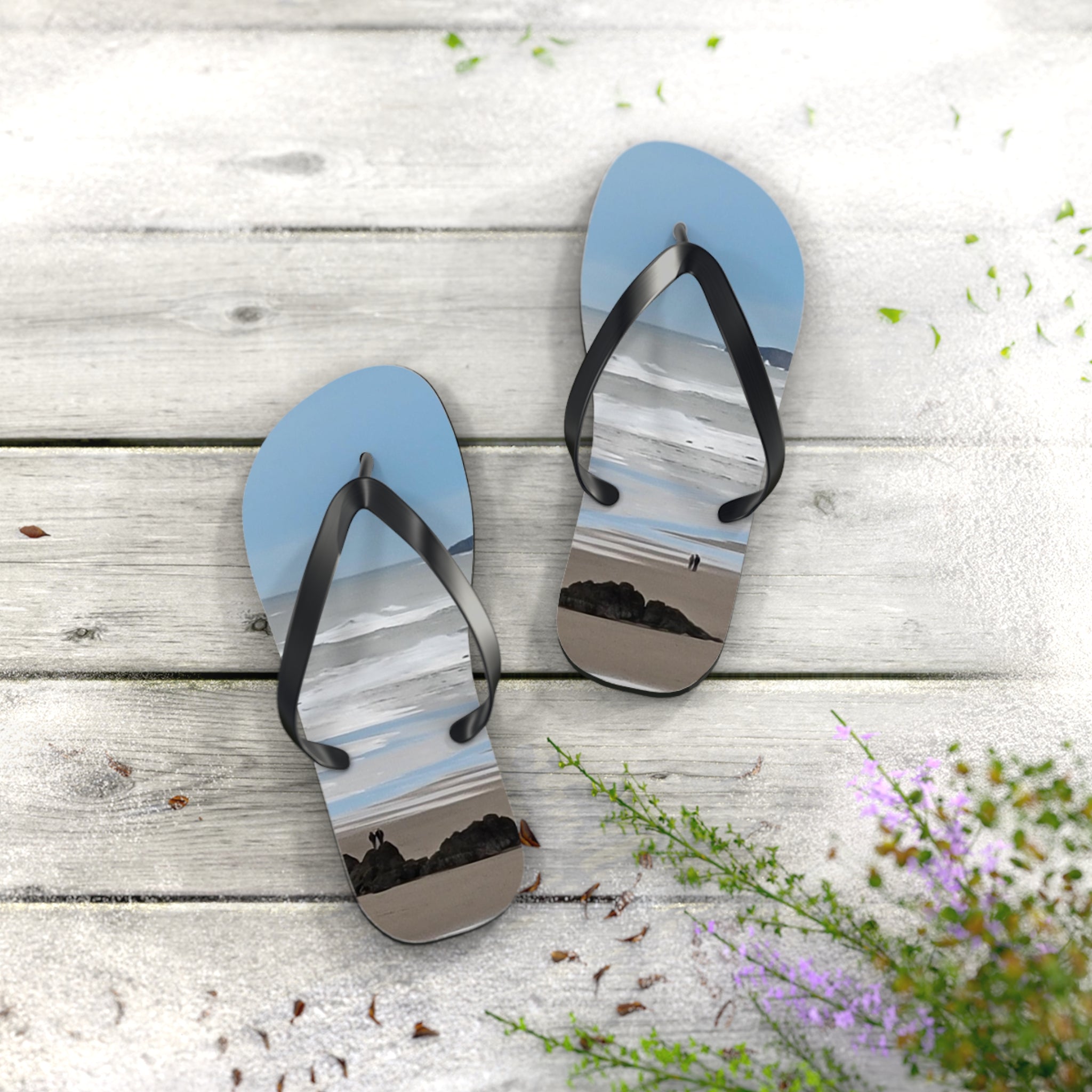 Flip-flops with a beach scene featuring two people on sand and rocks.
