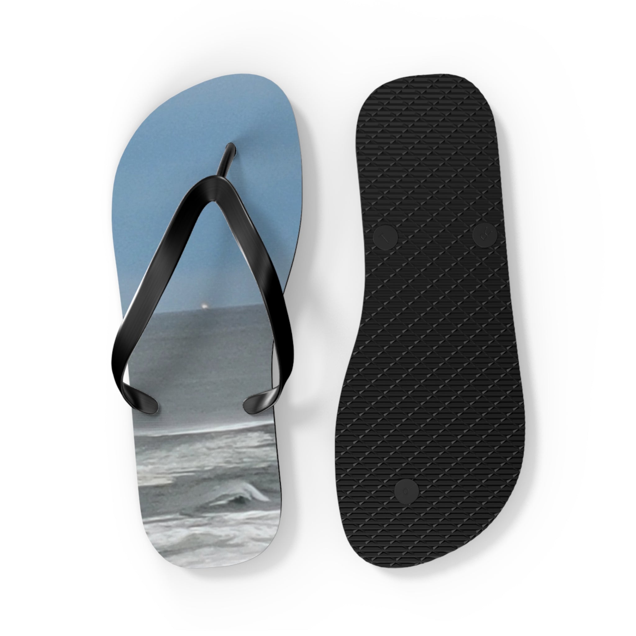 Two black flip-flops, one showing a beach scene, laid flat.