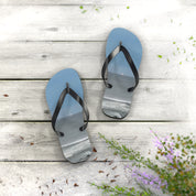 Blue flip-flops with a beach scene on the soles, resting on a wooden surface.