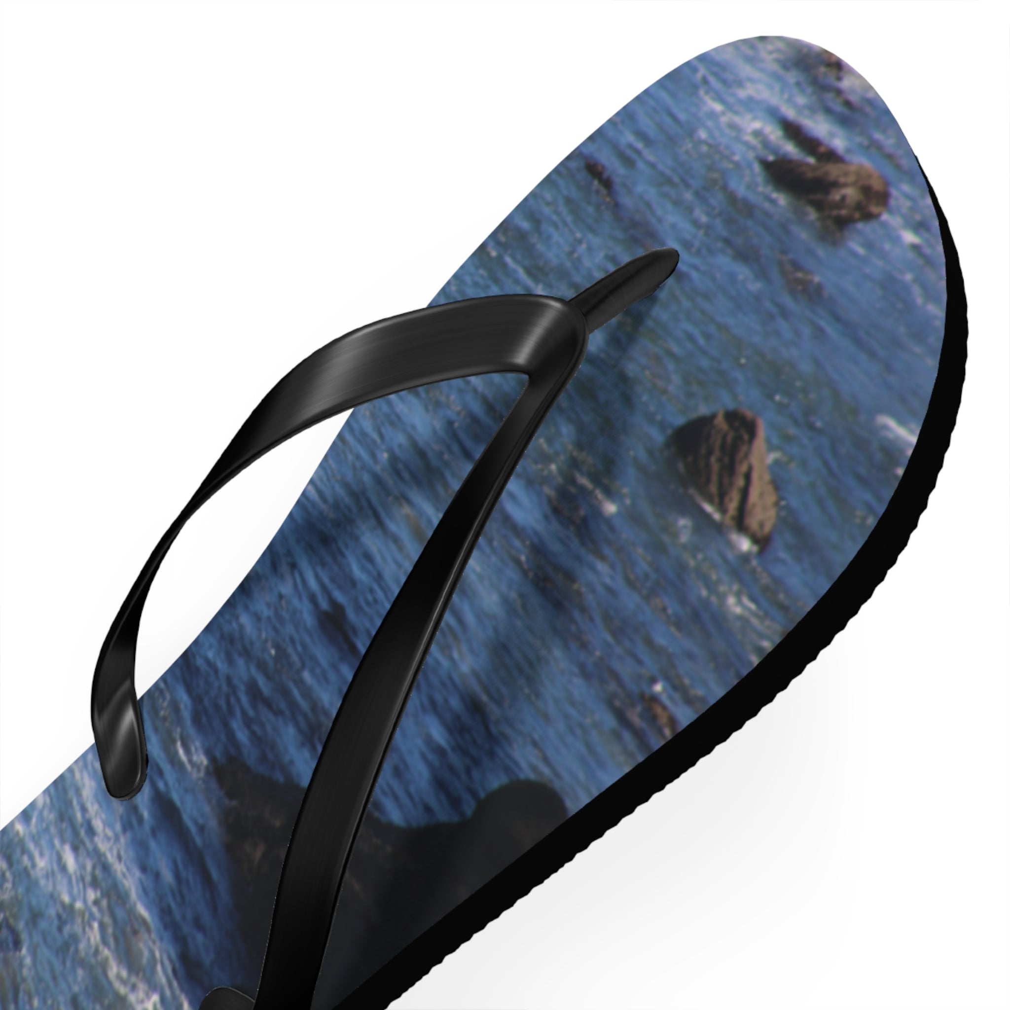 Black flip-flop with a dark blue ocean and rock print on the sole.