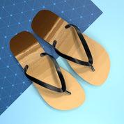 Brown flip-flops with black straps on a blue and white geometric background.
