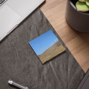 Wind turbines on a grassy hillside under a blue sky, on a sticky note.