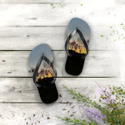 Flip-flops with a sunset tree silhouette on a white wooden surface.
