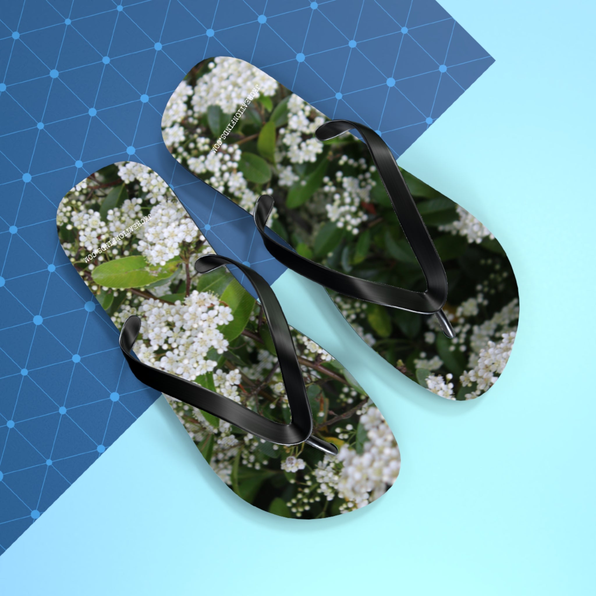 Flip-flops with white flowers and green leaves pattern.