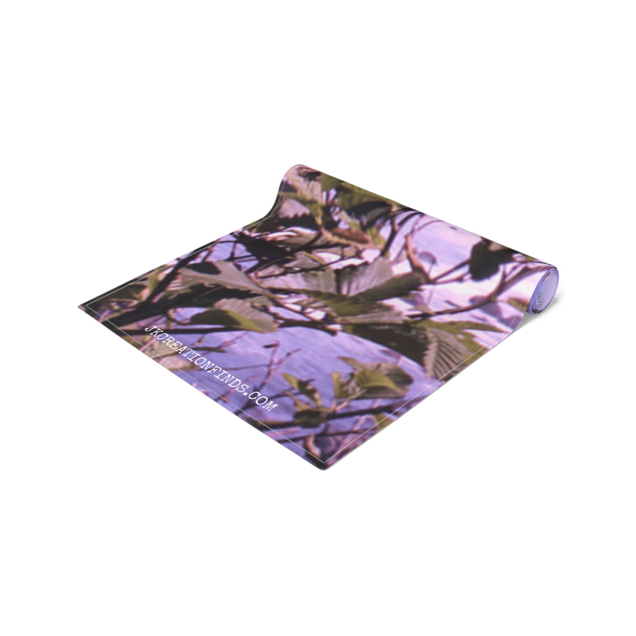 Rolled yoga mat with a nature-themed pattern and a website URL.