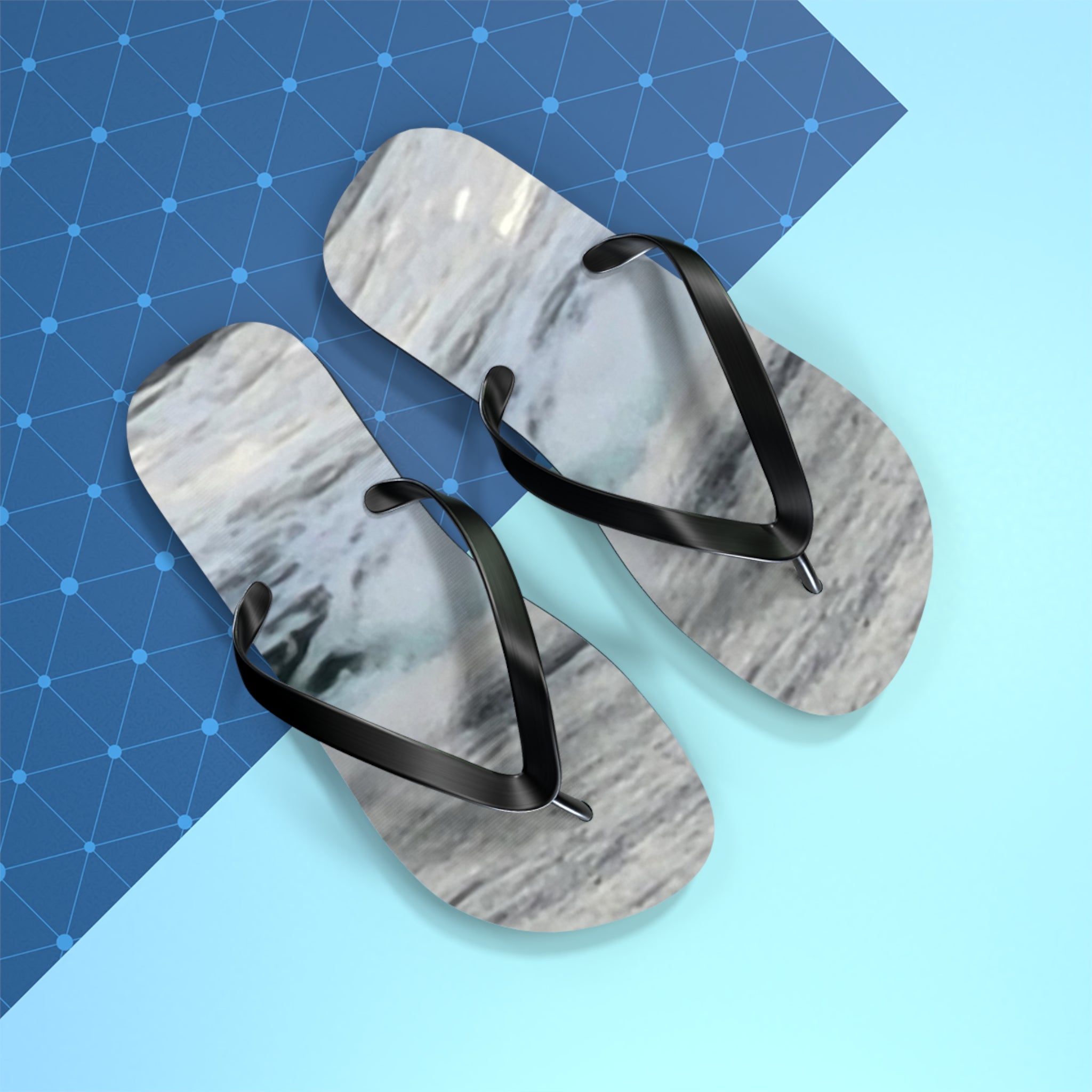 Flip-flops with marble pattern on black straps on blue and white background.