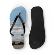 Flip-flops on a beach with ocean waves in the background.
