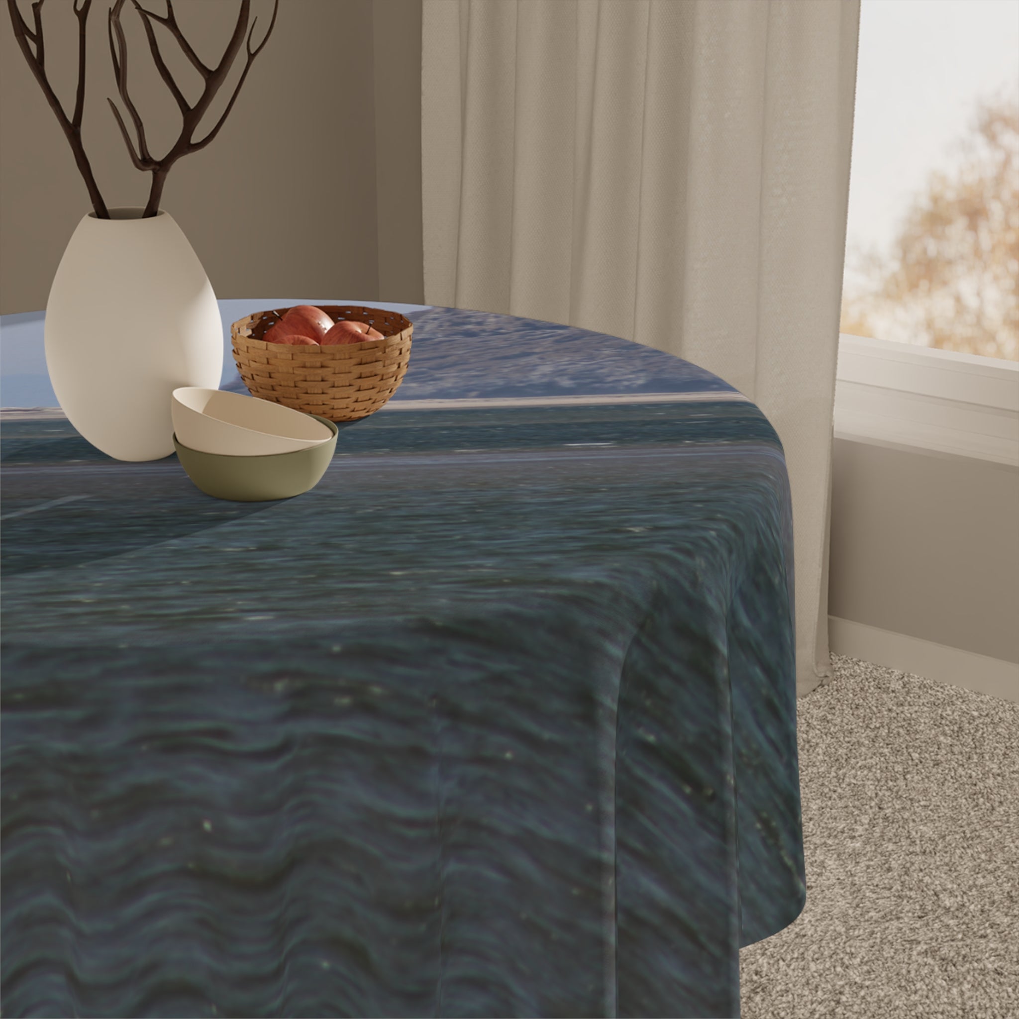 Round tablecloth with blue water pattern on a table with fruit bowl.