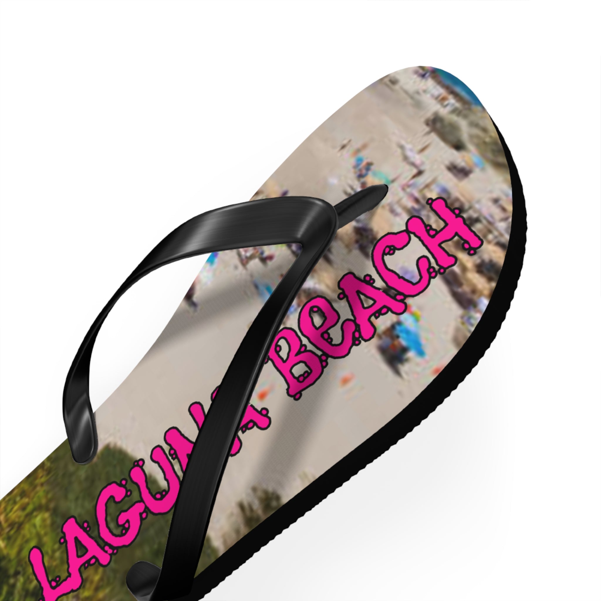 Black flip-flop with "LAGUNA BEACH" text on a beach scene.