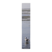 Seagull standing in shallow ocean waves with blurred background.