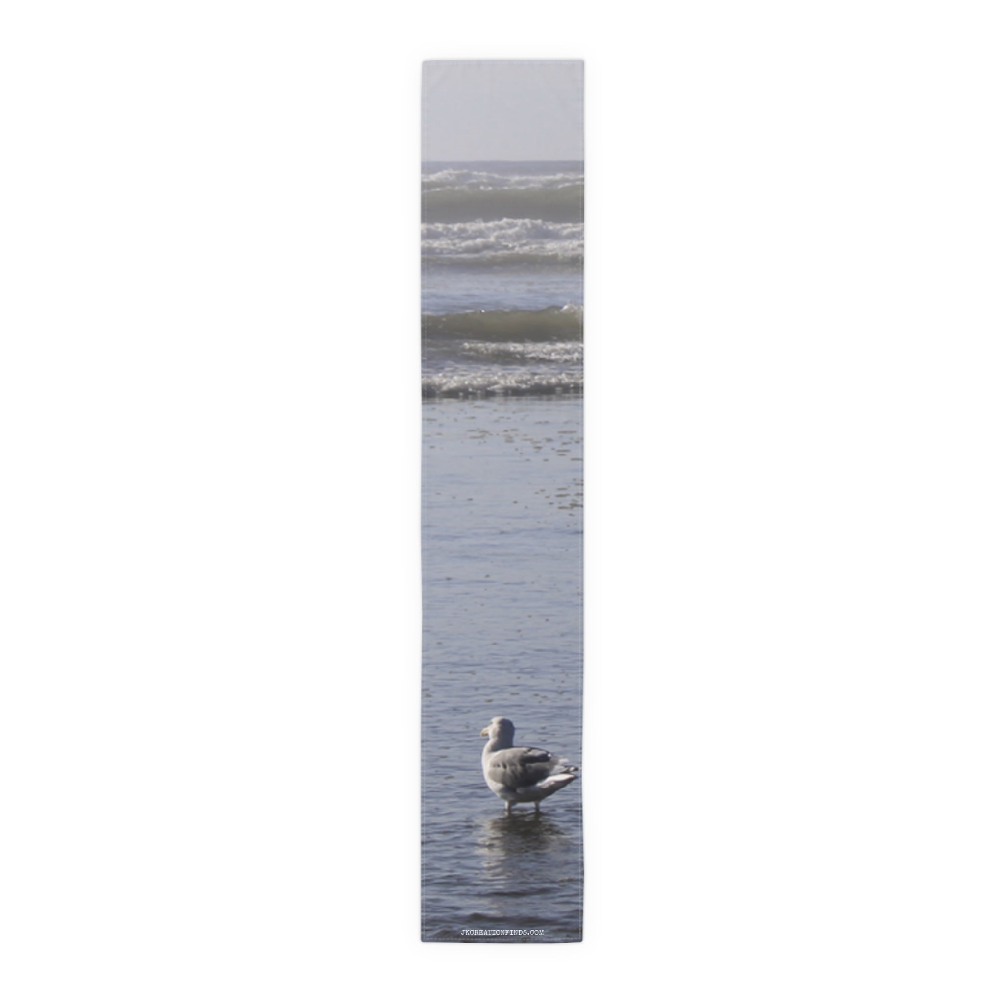 Seagull standing in shallow ocean waves with blurred background.
