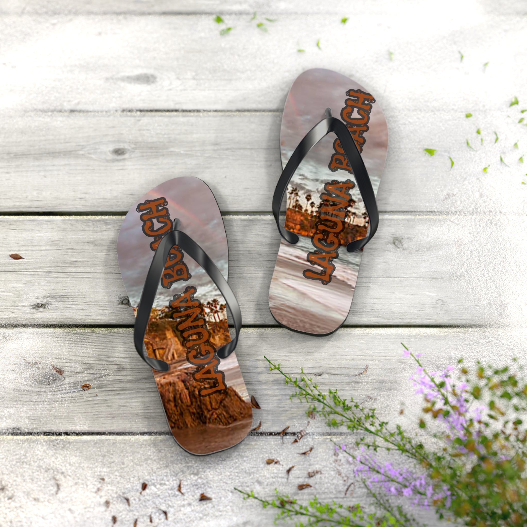 Flip-flops with "Laguna Beach" text and ocean landscape on wooden planks.