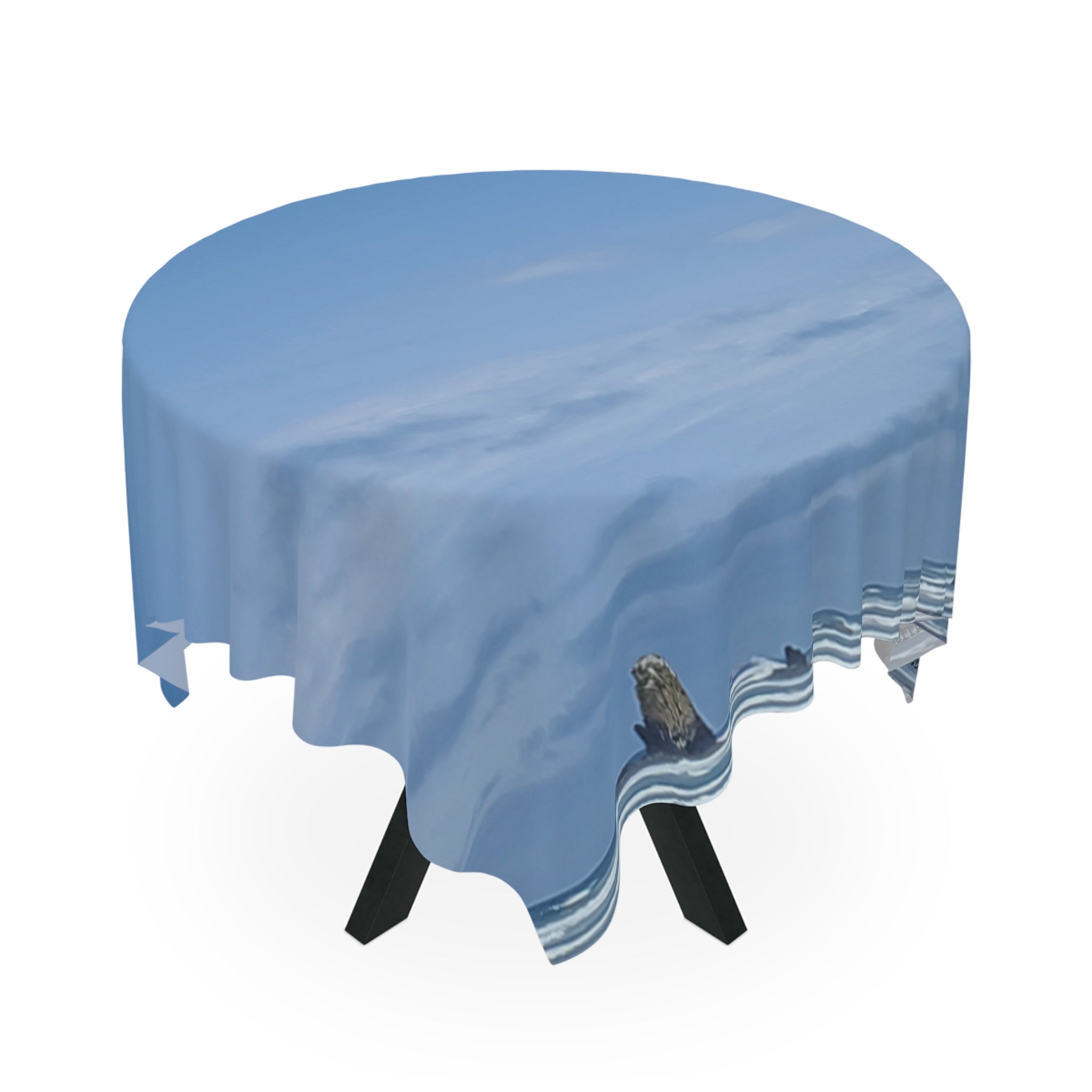 Round tablecloth with a sky and clouds pattern draped over a table.