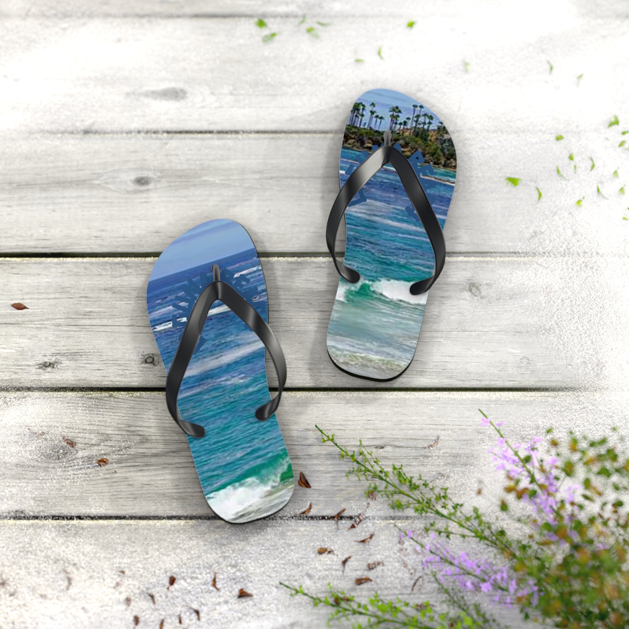 Flip-flops with ocean wave and palm tree scene on a wooden deck.