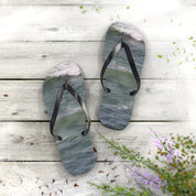 Flip-flops with ocean wave pattern on white wooden planks.
